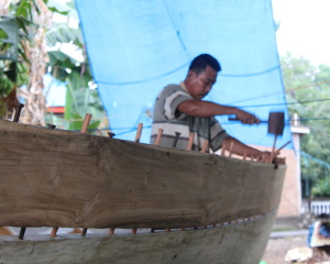A worker hammering the dowels into the planks in a boatyard in Tanah Beru. Photo: UNO/UI