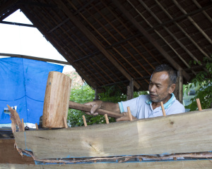 A worker hammering the dowels into the planks in a boatyard in Tanah Beru. Photo: UNO/UI