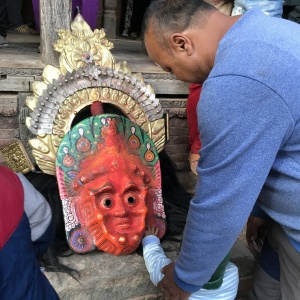 A man leads a toddler to a mask which has been taken off by a dancer who is resting during a local festival, Ganesh Temple, Yecce, Nepal. (Photo: Renuka Gurung)