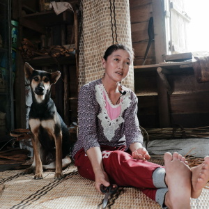 Ibu Yohana Anik, one of the knowledge holders of Bidayuh Jagoi traditional rattan weaving, in her workshop with her dog, 2022. (Photo: Sepatokimin Initiative)