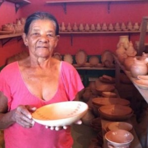 Local potter, Emília, holds a pot in the small storage room from the community. (Photo: Ana Carolina Brugnera)