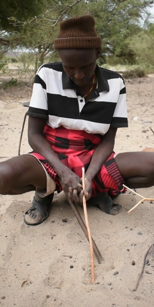 Man smoothing an arrow shaft with a stone flake, East Turkana, Kenya, 2022 (Photo: Johnathan Reeves)