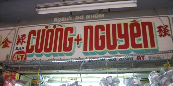 Sign from a shop selling aluminium products. Dozens of traditional Vietnamese coffee filters hang underneath. (Photo: logicalthings, licensed under CC BY-NC 2.0.)