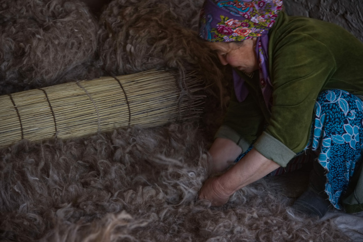 A skilled older craftswoman lays out uniform layers of wool to ensure the quality of the resulting felt. Photo: Bob Glennan